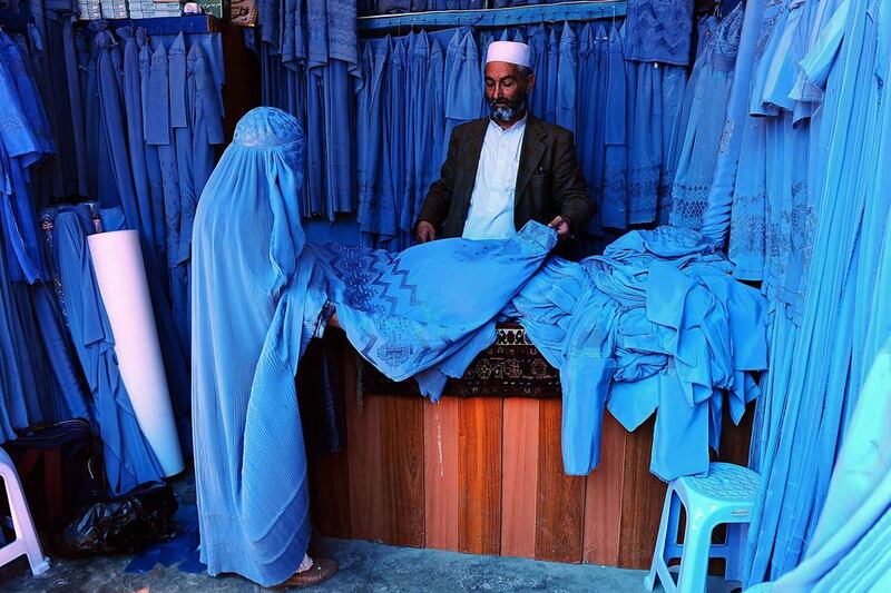 An Afghan shopkeeper shows a burqa to a customer at a bazaar in Herat, Afghanistan. Aref Karimi /AFP