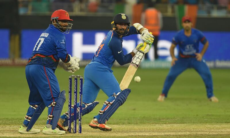 Indian batsman Dinesh Karthik (C) plays a shot as Afghan cricketer Mohammad Shahzad (L) looks on during the one day international (ODI) Asia Cup cricket match between Afghanistan and India at the Dubai International Cricket Stadium in Dubai on September 25, 2018. / AFP / ISHARA S.  KODIKARA

