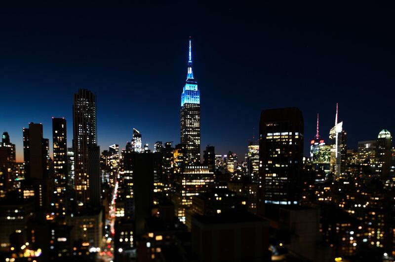 In a photo taken with a perspective control lens, the Empire State Building is illuminated light blue, Thursday, Oct. 8, 2020, in New York, in honor of what would've been John Lennon's 80th birthday, on Friday. (Photo by Evan Agostini/Invision/AP)