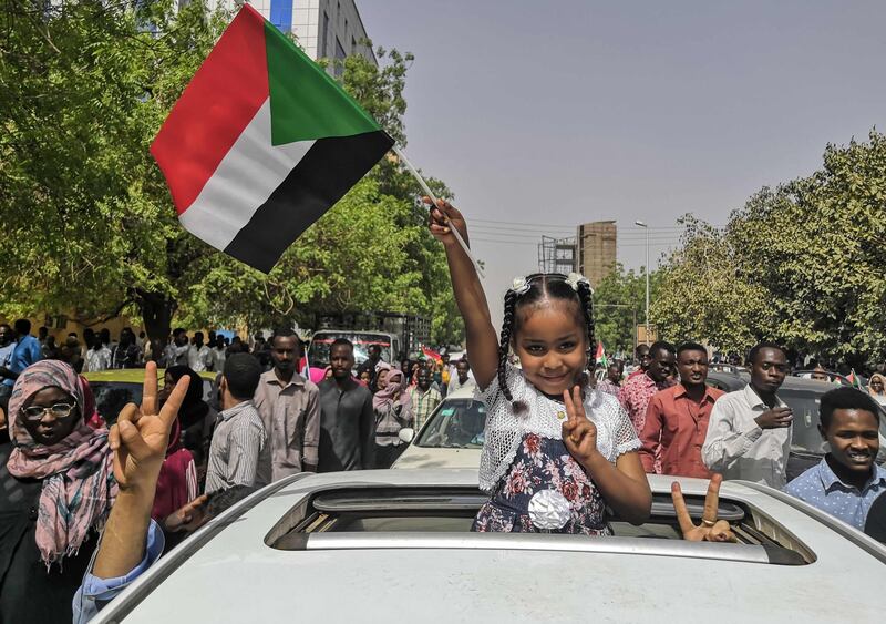 A Sudanese girl flashes the victory sign and holds the national flag. AFP
