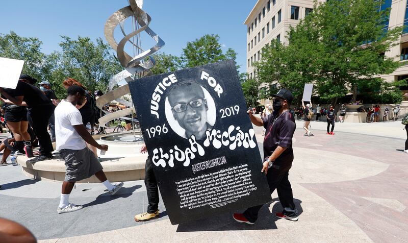 Demonstrators carry a giant placard during a rally over the death of Elijah McClain outside the police department in Aurora, Colorado. AP