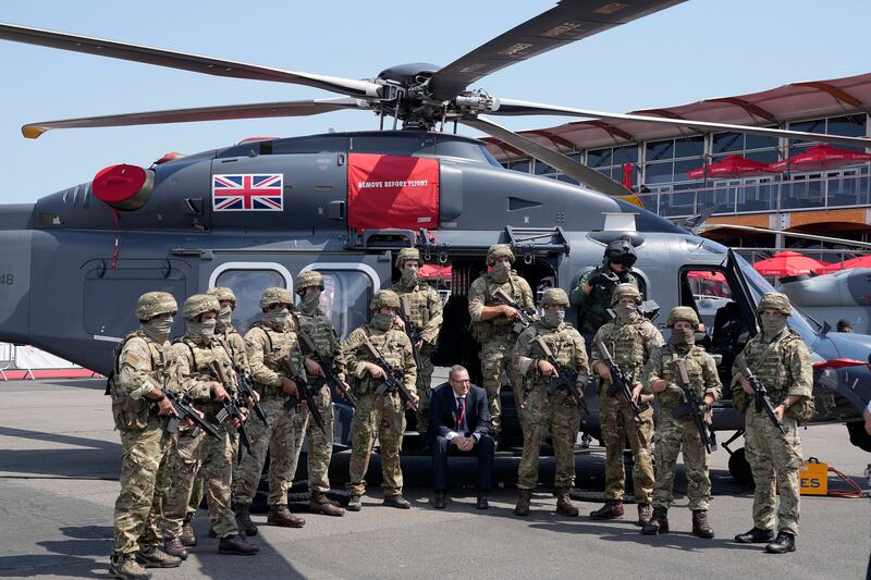 Soldiers pose beside a Leonardo helicopter. AP
