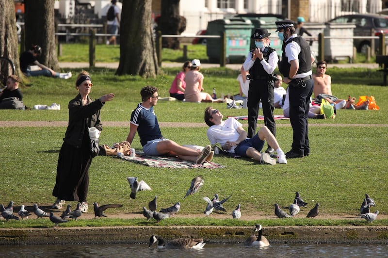 Police talk to people at Clapham Common, London. Temperatures exceeded 24°C in parts of Britain.