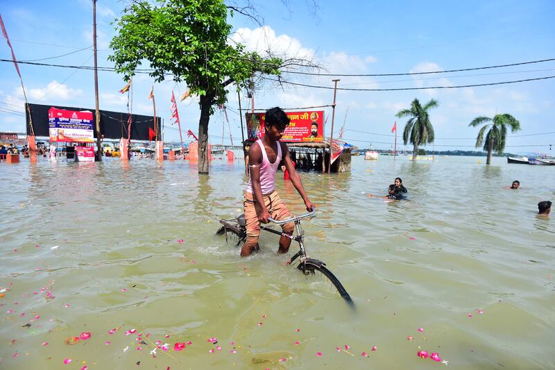 A boy cycles along a flooded road near the Ganges River in Allahabad as water levels rose after monsoon rains. AFP