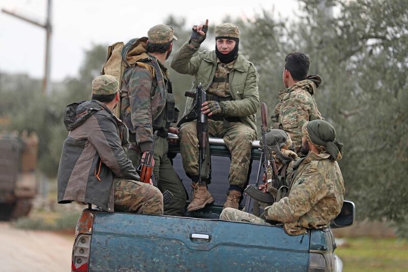 Turkish-backed Syrian fighters ride in the back of a pickup truck in the town of Sarmin, about 8 kilometres southeast of the city of Idlib in northwestern Syria.  AFP