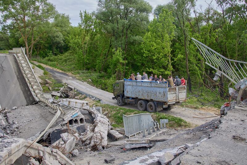 Ukrainians cross a makeshift bridge built next to a destroyed structure, in the Kharkiv region. EPA