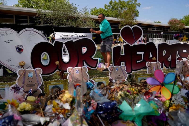 Brownsville school superintendent Rene Gutierrez adds a banner to a makeshift memorial that honours the victims of the school shooting. AP