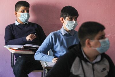 Students, mask-clad due to the COVID-19 coronavirus pandemic, attend a class at a school in in Sadr City, east of Iraq's capital Baghdad on December 7, 2020. (Photo by AHMAD AL-RUBAYE / AFP)