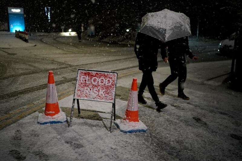 People walk past snow covered flood warning signs in Didsbury. Getty Images