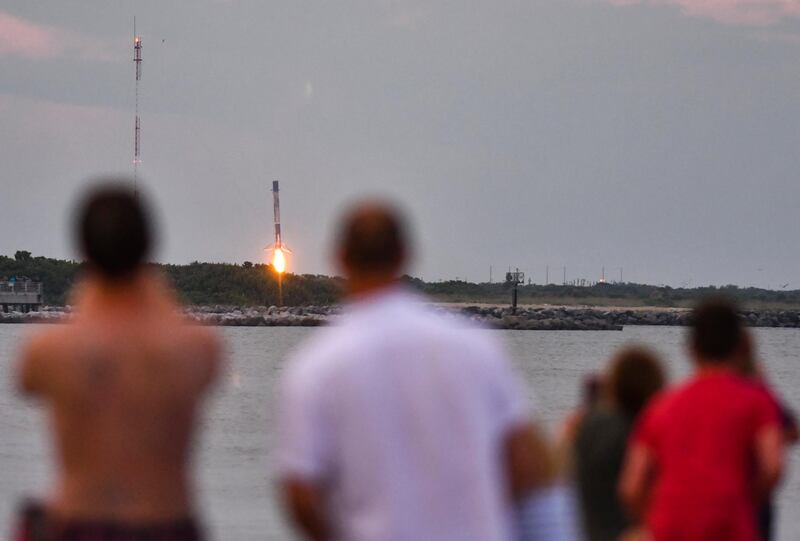 People at Cherie Down Park in Cape Canaveral, Florida, watch the booster landing of the SpaceX Falcon 9, on August 30. The rocket was carrying an Argentinian communications satellite known as SAOCOM-1B. Malcolm Denemark / Florida Today via AP