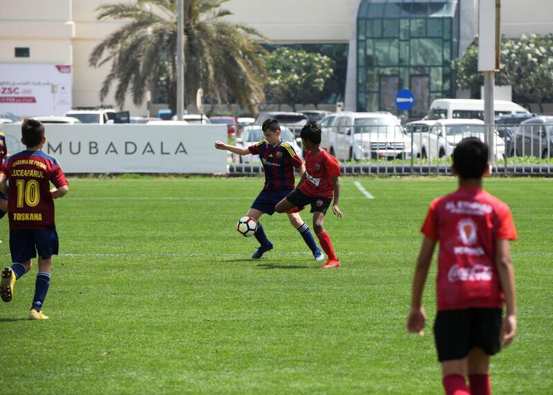 Abu Dhabi, United Arab Emirates - Etihad Sports Academy (plain red) vs Luceafarul from Romania (red/blue strips) under 12 age group on Abu Dhabi World Cup Day 1 at Zayed Sports City. Khushnum Bhandari for The National
