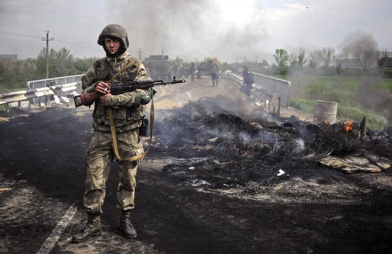 Russia’s economy has begun to spiral down and as tensions with neighbouring Ukraine escalate. Above, Ukrainian soldiers stay near a checkpoint they seized near the eastern city of Slaviansk. Roman Pilipey / EPA