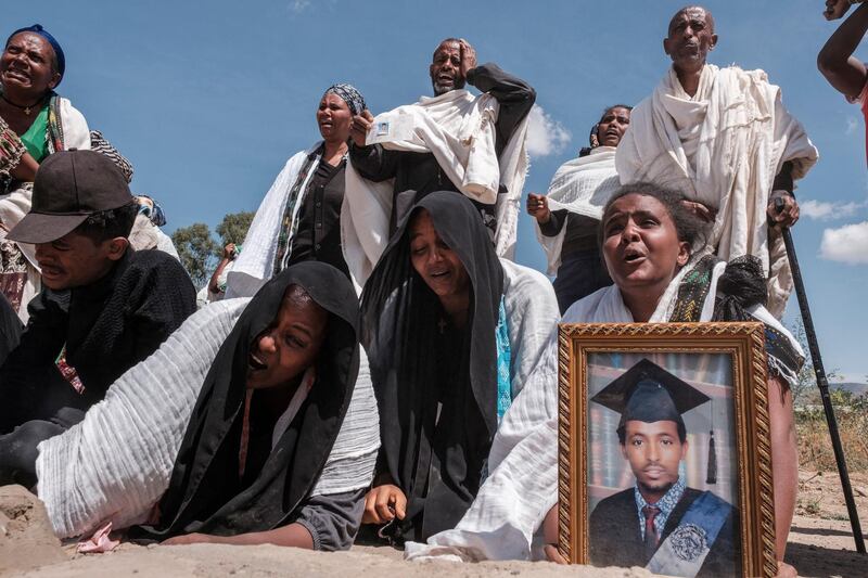 TOPSHOT - People react as they stand next to a mass grave containing the bodies of 81 victims of Eritrean and Ethiopian forces, killed during violence of the previous months, in the city of Wukro, north of Mekele, on February 28, 2021. Every phase of the four-month-old conflict in Tigray has brought suffering to Wukro, a fast-growing transport hub once best-known for its religious and archaeological sites. 
Ahead of federal forces' arrival in late November 2020, heavy shelling levelled homes and businesses and sent plumes of dust and smoke rising above near-deserted streets. 
Since then the town has been heavily patrolled by soldiers, Eritreans at first, now mostly Ethiopians, whose abuses fuel a steady flow of civilian casualties and stoke anger with Nobel Peace Prize-winner Abiy. / AFP / EDUARDO SOTERAS
