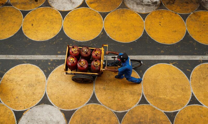 A man pushes a cart filled with liquefied petroleum gas (LPG) cylinders on a street painted with circles for people to maintain social distancing after a few restrictions were relaxed during an extended lockdown to slow the spread of the coronavirus in Mumbai, India. Reuters
