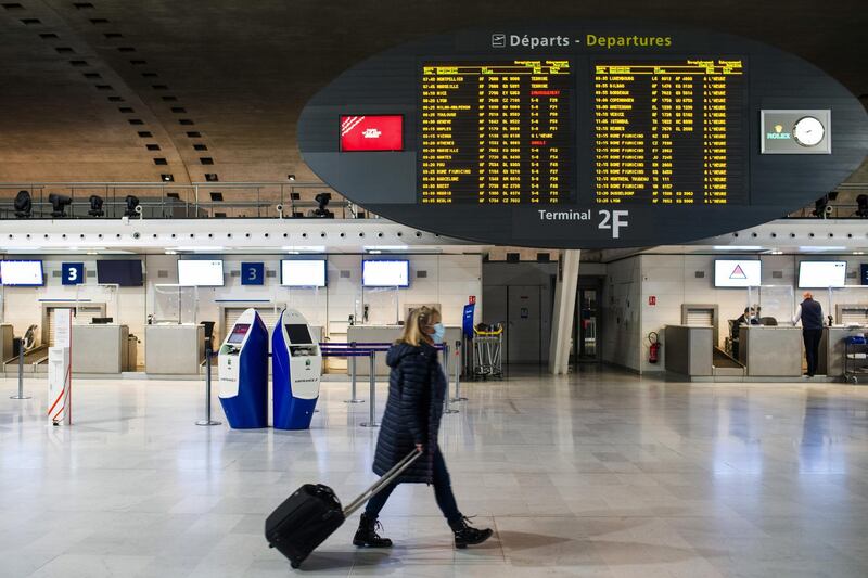 A traveler wearing a protective face mask pulls luggage along at a quiet Charles de Gaulle airport in France. Bloomberg