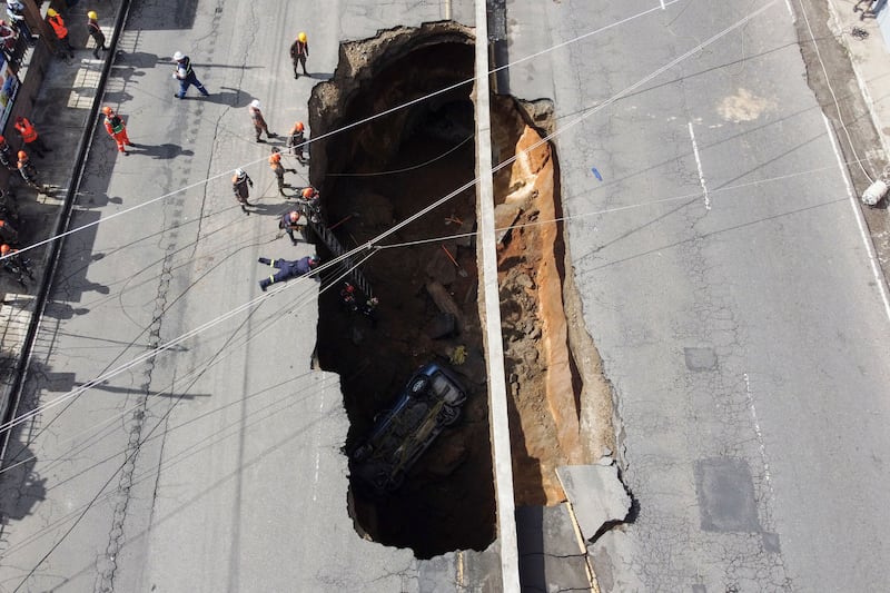 Aerial view of a giant hole in a road, caused by the collapse of a drainage system due to heavy rains that hit the country, in Villa Nueva, 15 km south of Guatemala City, on September 25, 2022.  - Four people traveling in a car suffered injuries and were taken to a hospital after they fell into a giant hole in a road, rescuers said.  (Photo by Johan ORDONEZ  /  AFP)