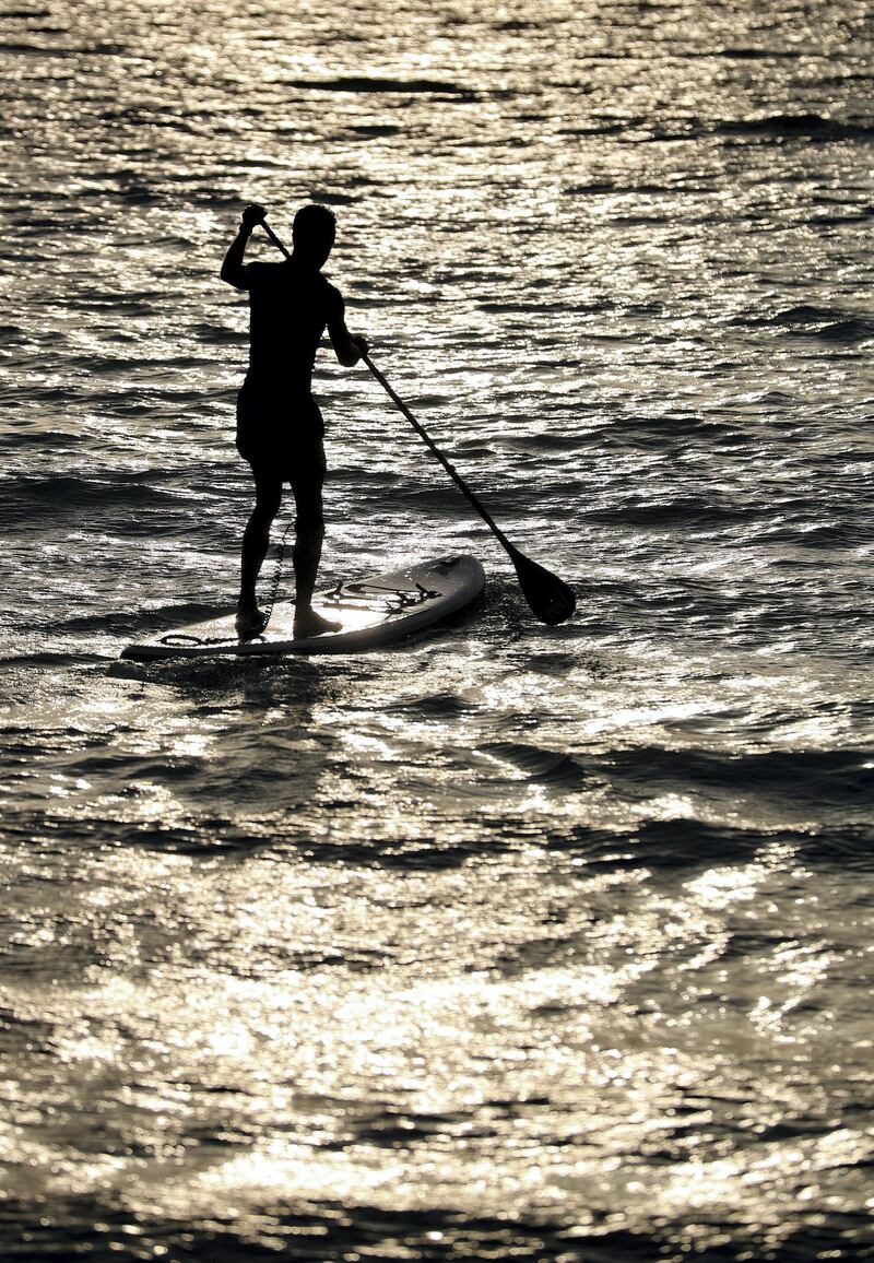 A man heads into the water to paddle board at sunset in Dubai on June 8th, 2021. Chris Whiteoak / The National. 
Reporter: N/A for News