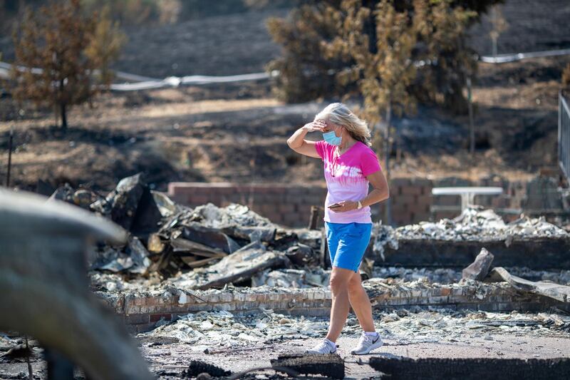 Carol Schafer walks past what remains of her home along Cantelow Road in Vacaville, California.  AP