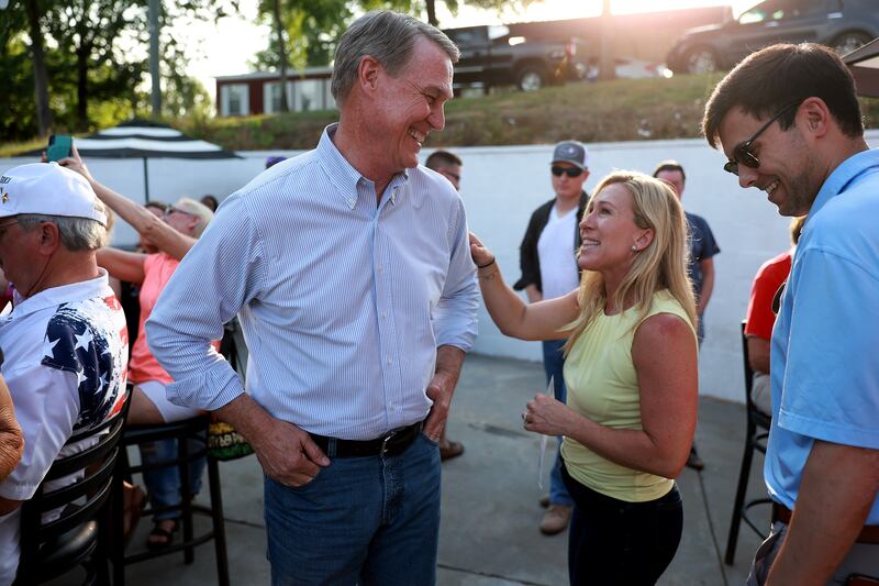 Mr Perdue and Ms Taylor Greene talk during a Bikers for Trump campaign event at the Crazy Acres Bar and Grill in Plainville, Georgia. Getty / AFP
