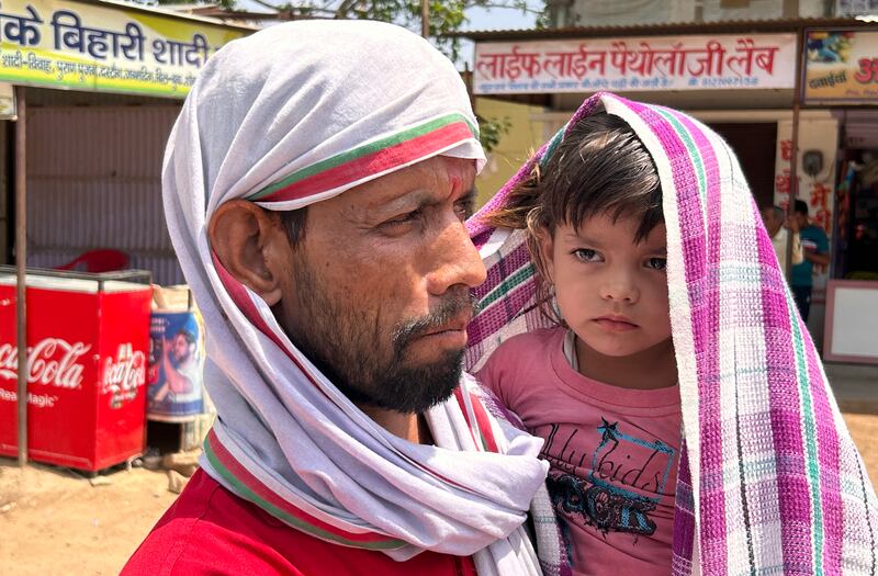 A man and a child covered with scarves to shield themselves from the blazing sunshine in Lalitpur, Uttar Pradesh state
