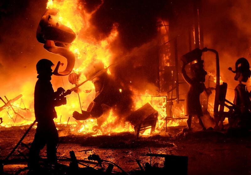 A fireman sprays water at figures of a monument as it burns during the finale of the Fallas festival in Valencia. Heino Kalis / Reuters