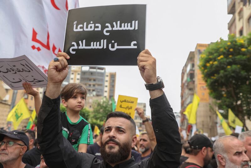 A man holds a sign reading 'weapons in defence of weapons' during the funeral of Hezbollah member Ahmad Ali Kassas, who died during an exchange of fire in Kahaleh. Reuters