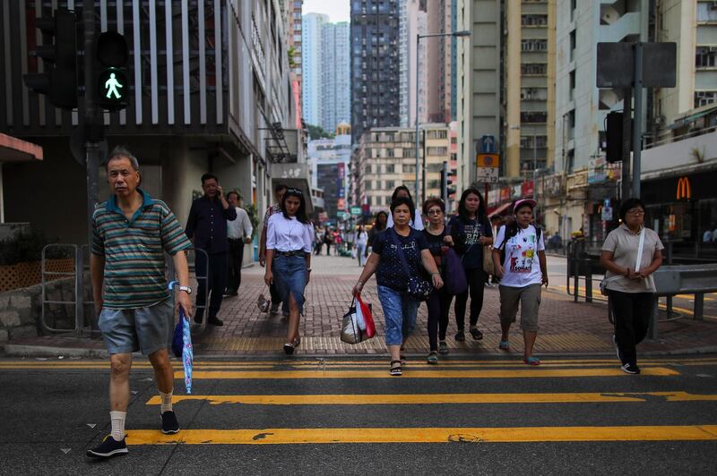 epa07867745 Pedestrians cross a road in Hong Kong, China, 25 September 2019. Hong Kong has an estimated population of 7,482,000 people, as of 2018, and has a total area of 1,100 square kilometers, making it one of the most densly populated areas in the world.  EPA/FAZRY ISMAIL
