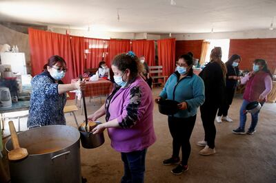 A volunteer serves food rations at a communal kitchen for poor people in Chile. Reuters