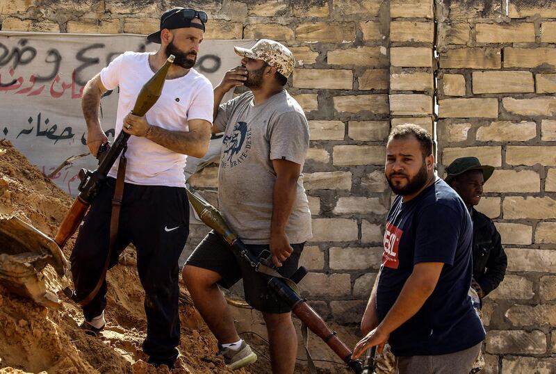 Libyan fighters loyal to the Government of National Accord (GNA) hold rocket-propelled grenade (RPG) launchers as they stand behind a dirt barrier during clashes with forces loyal to strongman Khalifa Haftar south of the capital Tripoli's suburb of Ain Zara, on April 10, 2019.  / AFP / Mahmud TURKIA
