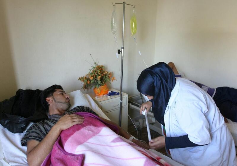 A Lebanese nurse, right, treats a Syrian man at a Lebanese medical charity clinic in the northern port city of Tripoli on Wednesday. Syrian refugees in Lebanon lack access to specialised medical care such as dialysis and cancer treatment, according to a new report from Amnesty International. AP Photo