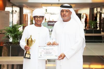 Khamis Al Jneibi shows off his trophy and certificate with his father Saleh Al Jneibi in Abu Dhabi. Pawan Singh / The National