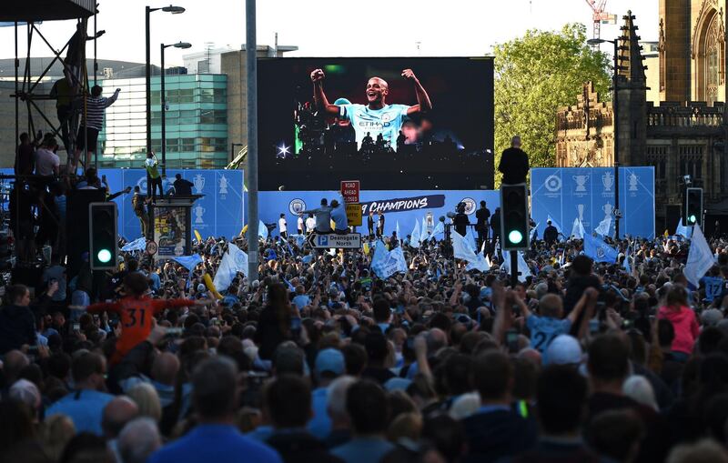 Manchester City football fans line the streets as they try to see the team show off the trophies on a stage, following an open-top bus parade through Manchester, northern England, to celebrate winning the 2019 Premier League title, the FA Cup and English League Cup. Pep Guardiola saluted Manchester City's history makers after they clinched the domestic treble with a swaggering 6-0 rout of Watford in the FA Cup final on Saturday. Just a week after winning a second successive Premier League crown, City's record-equalling FA Cup final victory made them the first English club to win the English title, FA Cup and League Cup in the same season.  AFP