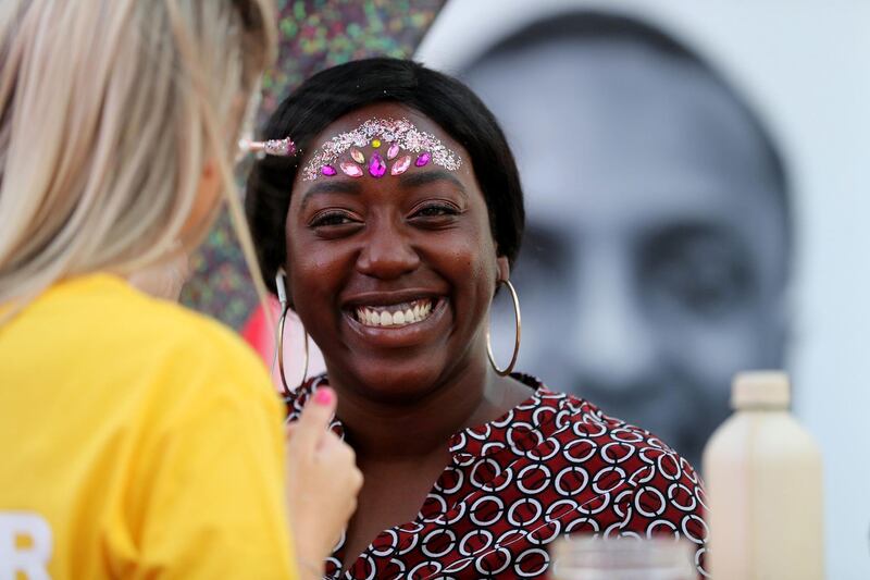 Dubai, United Arab Emirates - October 20, 2019: People put glitter on their faces at the One year to go celebrations. Sunday the 20th of October 2019. Burj Park, Dubai. Chris Whiteoak / The National