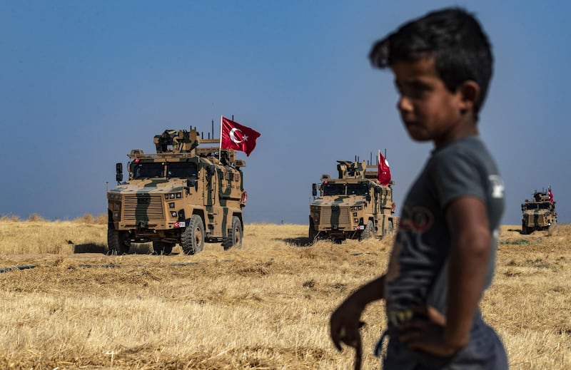 TOPSHOT - A Syrian boy watches as Turkish military vehicles, part of a US military convoy, take part in joint patrol in the Syrian village of al-Hashisha on the outskirts of Tal Abyad town along the border with Turkey, on October 4, 2019. The United States and Turkey began joint patrols in northeastern Syria aimed at easing tensions between Ankara and US-backed Kurdish forces. / AFP / Delil SOULEIMAN
