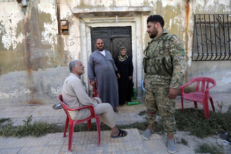 A Turkey-backed Syrian fighter speaks with poeple in the town of Tal Abyad, Syria. Reuters