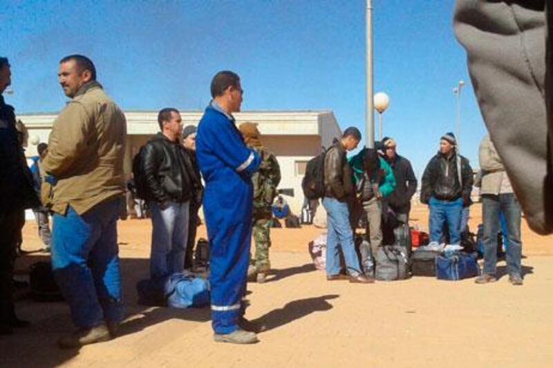 A militant, in camouflage uniform, stands among Algerian employees who were forced to leave the Ain Amenas natural gas complex on January 16. The hostage crisis at the complex left 37 foreigners dead. Kyodo / Handout / Reuters