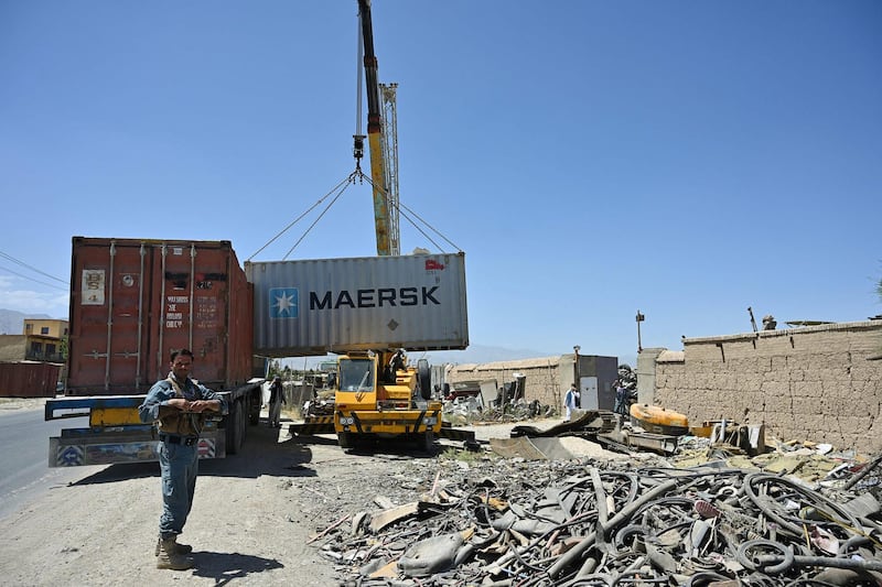 Policemen stand guard as workers unload a container at a junkyard near the Bagram Air Base. AFP