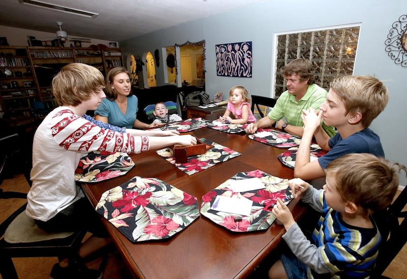 From left, Jo Armstrong, Julie Armstrong, Skylar Armstrong, Amelia Anderson, Nathan Anderson, Westley Armstrong and Dean Anderson sit together for a game at their home in Tucson, Arizona. At 42 with a blended family of five, Nathan Anderson runs an acupuncture clinic with his wife, Julie, also an acupuncturist. Combined, their monthly student loans bills approach $1,700. "More than we spend on groceries and kind of like having a second mortgage," Nathan said. Rick Scuteri / AP Photo