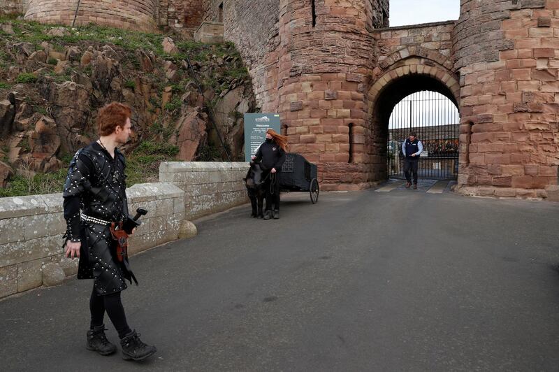 An actor dressed in medieval clothing stands outside Bamburgh Castle during its reopening to the public, following the easing of lockdown restrictions, in Northumberland. Reuters