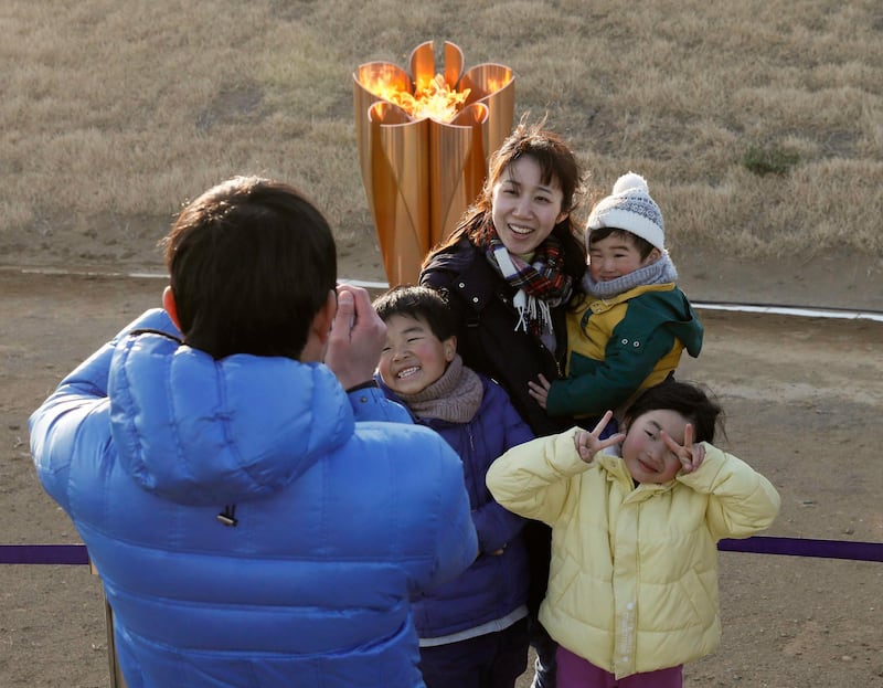 A family takes a selfie with the Olympic flame. EPA