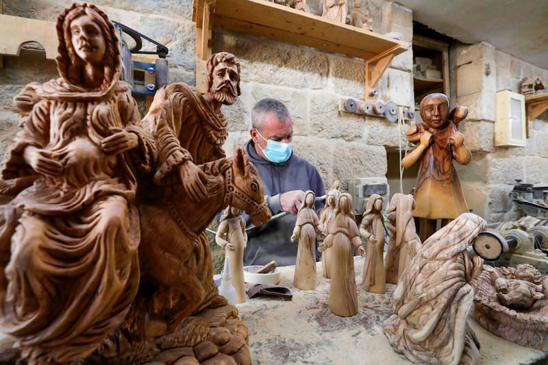 A Palestinian carpenter carves religious statues and figurines from olive wood at a shop near the Church of the Nativity, in the West Bank city of Bethlehem. AFP