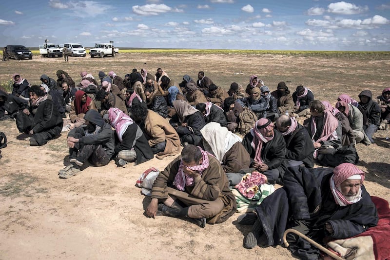 Men who surrendered to Syrian Democratic Forces waited ot be transported to prison, outside Baghouz, Syria, 8 March 2019.