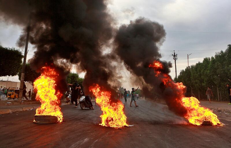 Anti-government protesters set fires and close a street during a demonstration in Baghdad. AP Photo