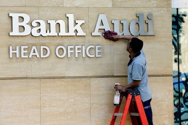 A worker cleans the logo of Bank Audi in Beirut. The lender is considering selling its Egyptian subsidiary. Reuters 