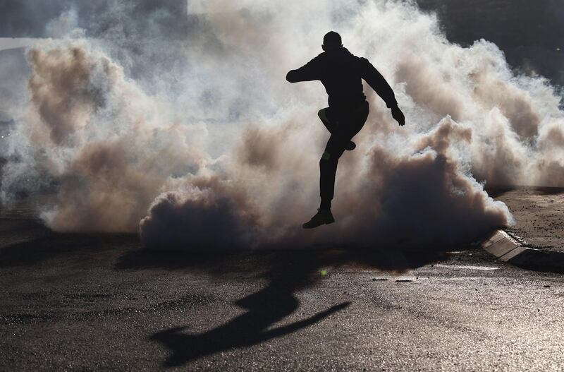 A Palestinian protester jumps over smoke from burning tires during clashes with Israeli soldiers near the Hawara checkpoint, south of the occupied West Bank city of Nablus. AFP