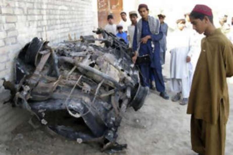 Tribesmen look at a vehicle destroyed by a missile attack in Mir Ali on the outskirts of Miranshah, near the Afghan border, November 1, 2008.