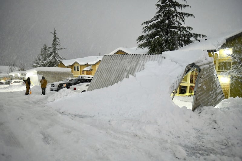 A pair of residents at the Cedar Park apartments in Grass Valley take a break from shovelling snow during another blizzard earlier this week. AP