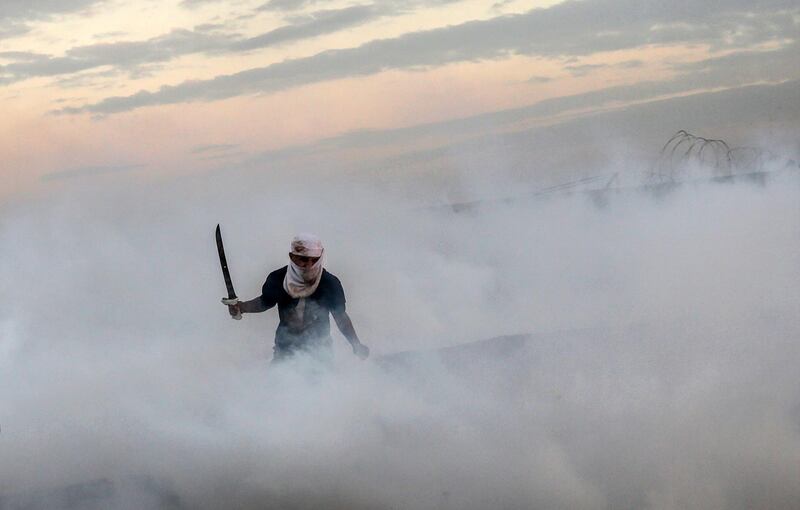 A Palestinian protester runs for cover from Israeli tear-gas during clahses near the border between Israel and Gaza Strip in the east Gaza Strip.  EPA