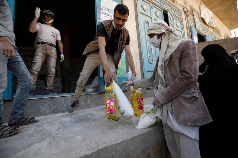 epa08966308 Aid workers wearing protective face masks distribute free food rations to Yemenis amid concerns over the coronavirus COVID-19 pandemic, in Sanaâ€™a, Yemen, 24 January 2021 (Issued 26 January 2021). Countries around the world are fighting with the second wave of the SARS-CoV-2 coronavirus which causes the COVID-19 disease.  EPA/YAHYA ARHAB