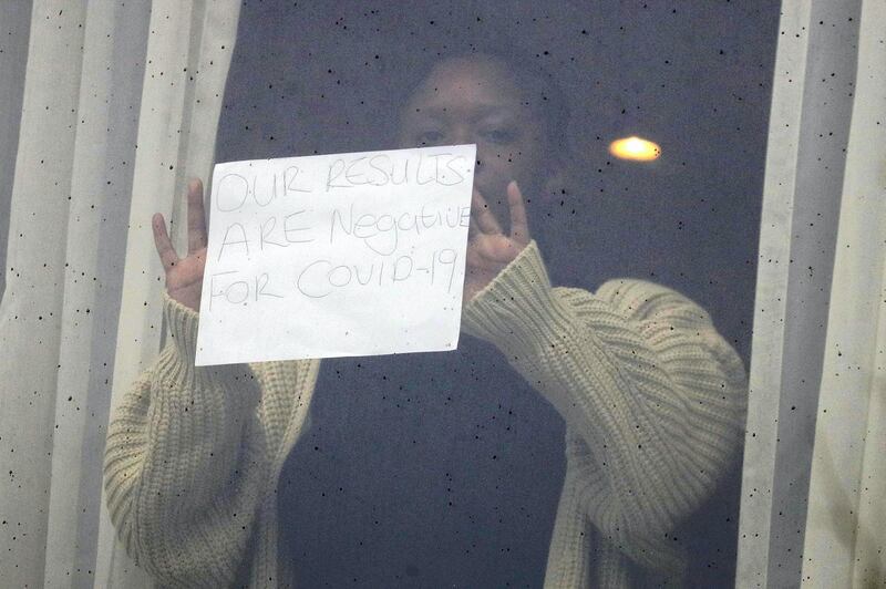 A woman holds up a sign for the media against the window at the Radisson Blu Edwardian Hotel, near London's Heathrow Airport, where passengers will remain during a 10-day quarantine period after arriving in England at the airport Tuesday Feb. 16, 2021. New regulations require people arriving from one of the "coronavirus red list" countries to quarantine at one of the Government's managed quarantine hotel facilities.(AP Photo/Kirsty Wigglesworth)